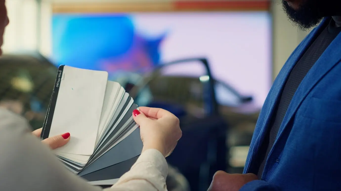 Сотрудник автосалона предоставляет клиенту выбор оттенков на цветовом круге.